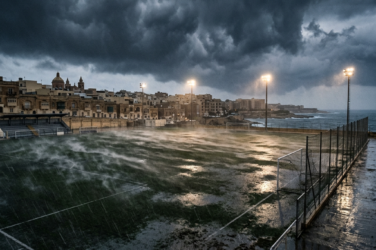 Rain-soaked football pitch beside a coastal town under dark storm clouds